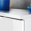 A close-up view of the top edge of a white cabinet with a glossy finish, showing the detail of the countertop and a drawer front. Produktbild-Vorschau