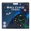 The image shows the packaging of a wall clock with a space theme. The clock itself is visible on the packaging. Náhled obrázku produktu