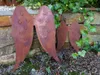 Three rusty metal angel wings are placed in a garden setting against a stone wall with ivy. Produktbild-Vorschau
