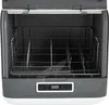 An open dishwasher with racks inside, placed on a white and gray surface. Náhled obrázku produktu