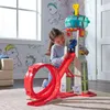 A young girl playing with a toy tower and race track in a room with Paw Patrol themed wallpaper. Náhľad obrázku produktu