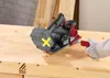 A person wearing a glove is using a cordless planer on a wooden workbench. Produktbild-Vorschau
