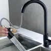 A person is using a black kitchen faucet with a pull-out spray head in a modern kitchen sink. Produktbild-Vorschau