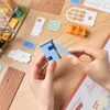 Hands assembling a miniature model house kit on a wooden table. Anteprima dell’immagine prodotto