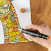 A hand holding a marker and coloring a detailed drawing. Náhľad obrázku produktu
