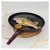 A cooked fish with lemon slices and rosemary in a frying pan on a wooden board. Podgląd zdjęcia produktu