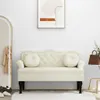 A cream-colored velvet bench with tufted detailing and two round cushions is placed against a white wall. A framed abstract artwork hangs above the bench, and a gold-framed arched mirror with a coat hanging on it is to the left. A small side table with a b Produktbild-Vorschau