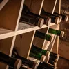 A close-up view of a wooden wine rack filled with wine bottles. Voir les images du produit