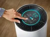 A hand is shown interacting with the control panel of an air purifier. Produktbild-Vorschau