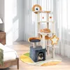 A multi-level cat tree with various platforms, a hammock, a house, and toys, placed in a bedroom setting next to a bed and a nightstand. Anteprima dell’immagine prodotto