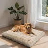 A golden retriever dog is lying on a plush beige dog bed in a well-lit room with a large window and a potted plant. Náhľad obrázku produktu