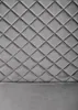 A close-up, full-frame shot of a gray quilted headboard and a portion of the bed frame. Produktbild-Vorschau