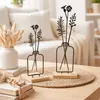 Two decorative metal flower vase sculptures on a wooden table, with a couch and dried flowers in the background. Produktbild-Vorschau