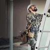 A construction worker in camouflage uniform climbing a ladder. Voir les images du produit