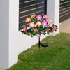 Solar-Gartenleuchte mit rosa Blumen und grünen Blättern, in grünem Gras neben einer weißen Wand aufgestellt Anteprima dell’immagine prodotto
