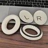 Close-up of replacement ear pads for headphones, placed on a laptop keyboard and a wooden surface. Anteprima dell’immagine prodotto