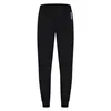 A black pair of sweatpants with a white logo on the left leg. Produktbild-Vorschau