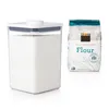 A clear plastic food storage container filled with white flour is shown next to a bag of all-purpose flour. Produktbild-Vorschau