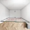 A shower enclosure with glass doors and silver metal framing, set against a white tiled wall and a wooden floor. Produktbild-Vorschau