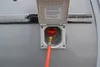 A close-up view of an outdoor gas connection point on a vehicle, with an orange hose connected. Voir les images du produit