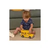 A young child is playing with a toy school bus on the floor next to a couch. Anteprima dell’immagine prodotto