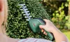 A person is using a Bosch hedge trimmer to trim a green bush in a garden. Anteprima dell’immagine prodotto