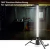 A tall, illuminated LED work light on a tripod stand in a dimly lit industrial or basement-like setting. Produktbild-Vorschau