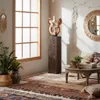 A bohemian-style living room with a wooden column, plants, rugs, and decorative items. Produktbild-Vorschau