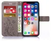 A gray wallet-style phone case with a floral design is open, showing credit cards and euro banknotes inserted, and a smartphone displaying its home screen. Produktbild-Vorschau