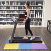 A woman is exercising on a treadmill in a room with bookshelves in the background. Voir les images du produit