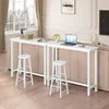 A white bar table with two stools in a living room setting, with a laptop and a vase of flowers on the table. Produktbild-Vorschau
