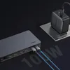 A Ugreen USB-C docking station is shown connected to cables, with a power adapter plugged into a wall socket in the background. Produktbild-Vorschau