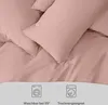 Close-up of pink bedding with icons indicating washability and dryer suitability. Voir les images du produit