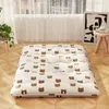 A floor mattress with a bear pattern is laid out on a wooden floor in front of a window with sheer curtains. Náhled obrázku produktu