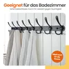 A black coat rack with towels hanging on it, mounted on a white panelled wall. Produktbild-Vorschau