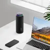 A black cylindrical speaker with a colorful light ring on top sits on a white desk next to a laptop and a smartphone. Náhľad obrázku produktu