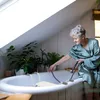 An elderly woman is using a bath seat in a bathtub. Voir les images du produit