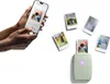 A person is holding a smartphone, and several printed photos are scattered around a small green printer. Náhľad obrázku produktu