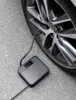 A portable air compressor is connected to a car tire, showing the tire pressure on its display. Produktbild-Vorschau