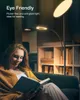 A woman is reading a book while sitting on a couch, illuminated by a floor lamp. Podgląd zdjęcia produktu