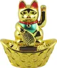 A golden lucky cat figurine sitting in a boat filled with coins. Produktbild-Vorschau