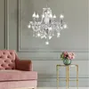 A crystal chandelier hangs above a pink velvet sofa and a small gold side table with a vase of flowers. Anteprima dell’immagine prodotto