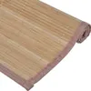 A close-up view of a rolled-up bamboo placemat with a pink woven edge. Náhled obrázku produktu