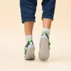 The back view of a child's feet wearing gray and green shoes and white socks. Produktbild-Vorschau