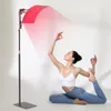 A woman is performing a yoga pose in front of a red light therapy panel. Produktbild-Vorschau