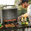 A man is grilling food on a gas grill outdoors. Produktbild-Vorschau