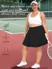 A woman wearing a black tennis skirt and white sports bra on a tennis court. Produktbild-Vorschau