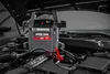 A car jump starter power pack is placed on top of a car engine with the hood open. Anteprima dell’immagine prodotto