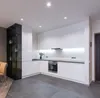 A modern kitchen with white cabinets and a dark tiled floor. Produktbild-Vorschau