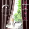 A close-up of a brown velvet curtain with a decorative birdcage candle holder and books on a table in front of a window with greenery outside. Produktbild-Vorschau